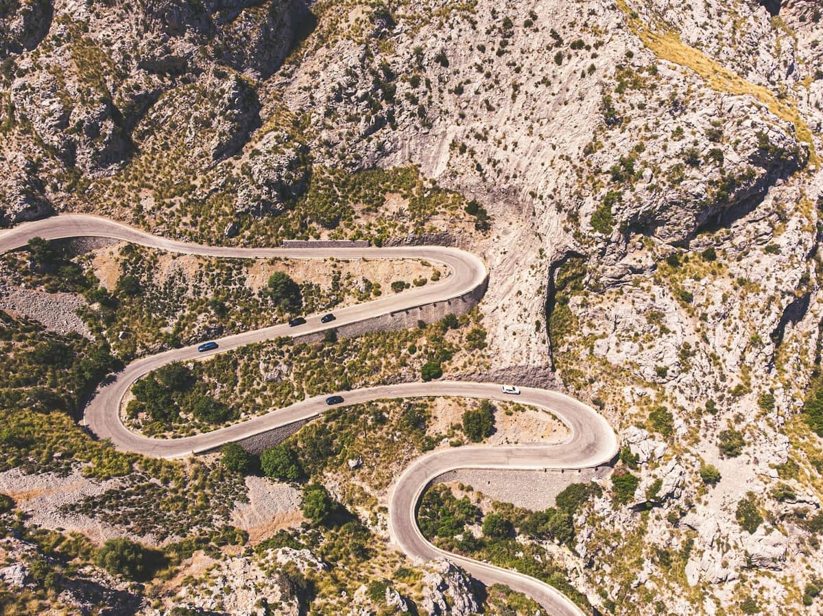 Vue aérienne d'une route de montagne sinueuse avec des virages en épingle à cheveux serrés traversant un terrain rocheux dans les montagnes de la Tramuntana à Majorque.