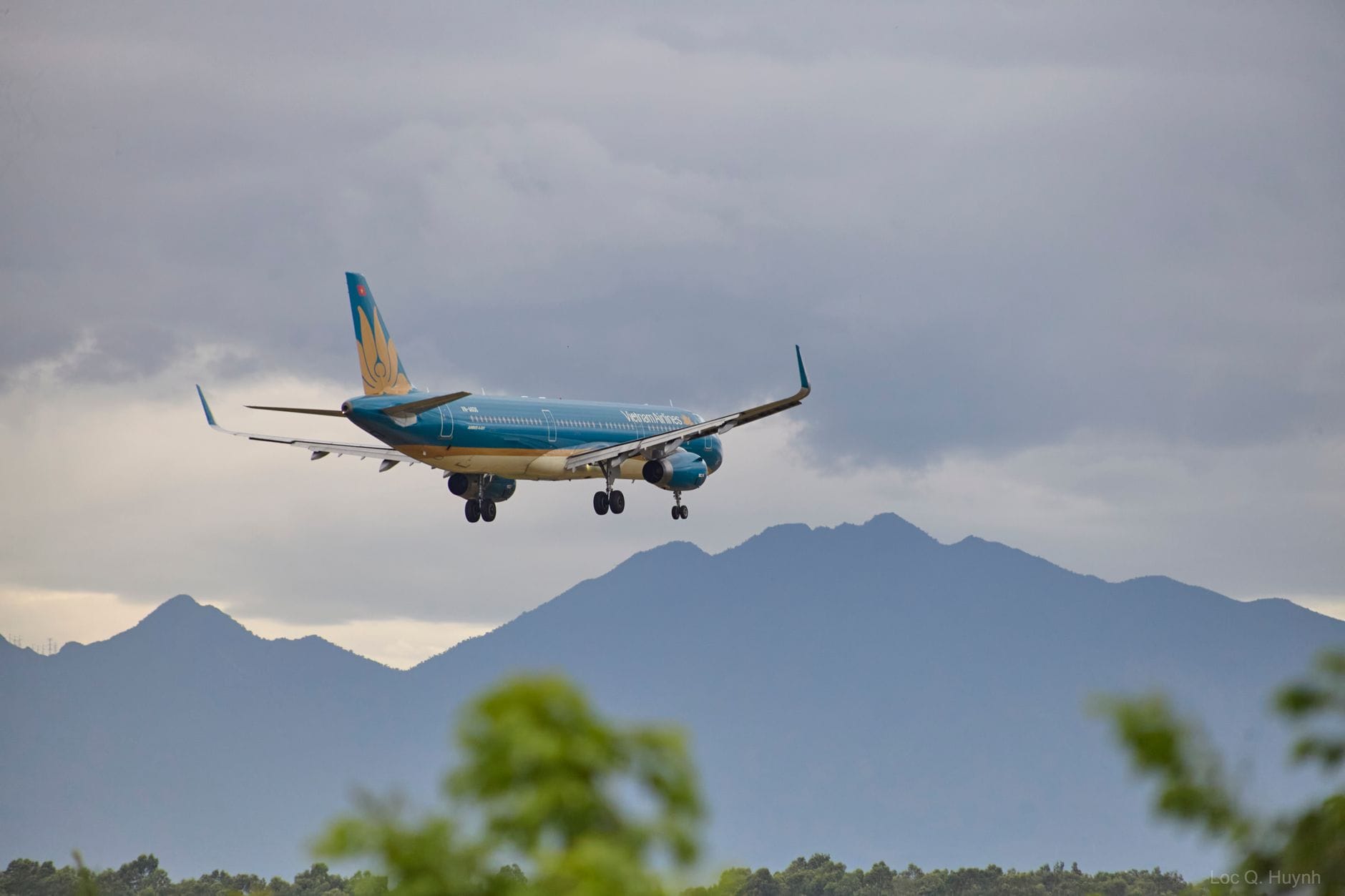เครื่องบินสายการบิน Vietnam Airlines กำลังลงจอด มีภูเขาดานังเป็นฉากหลัง บรรยากาศขาเข้าสนามบินนานาชาติดานัง