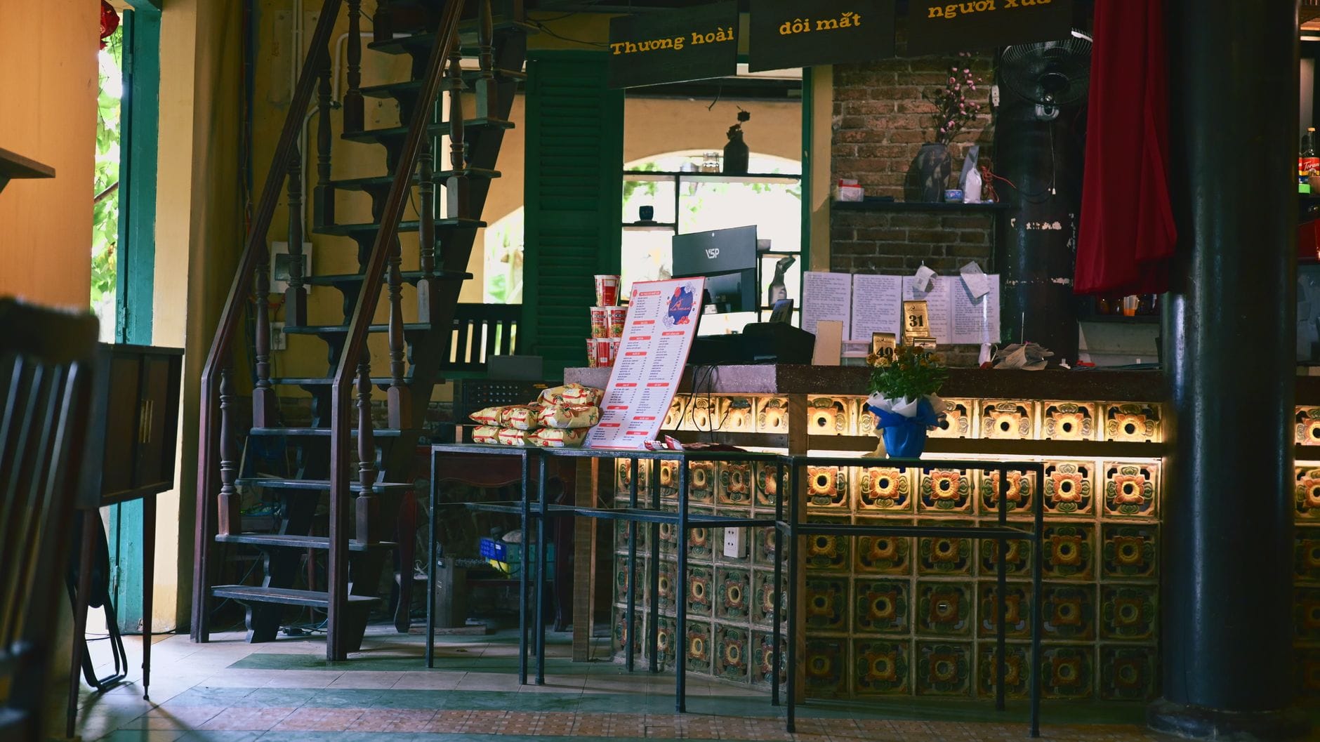 ภายในร้านกาแฟเวียดนามที่มีการตกแต่งแบบดั้งเดิม เคาน์เตอร์กระเบื้อง บันไดไม้ และบรรยากาศที่อบอุ่นใน ดานัง