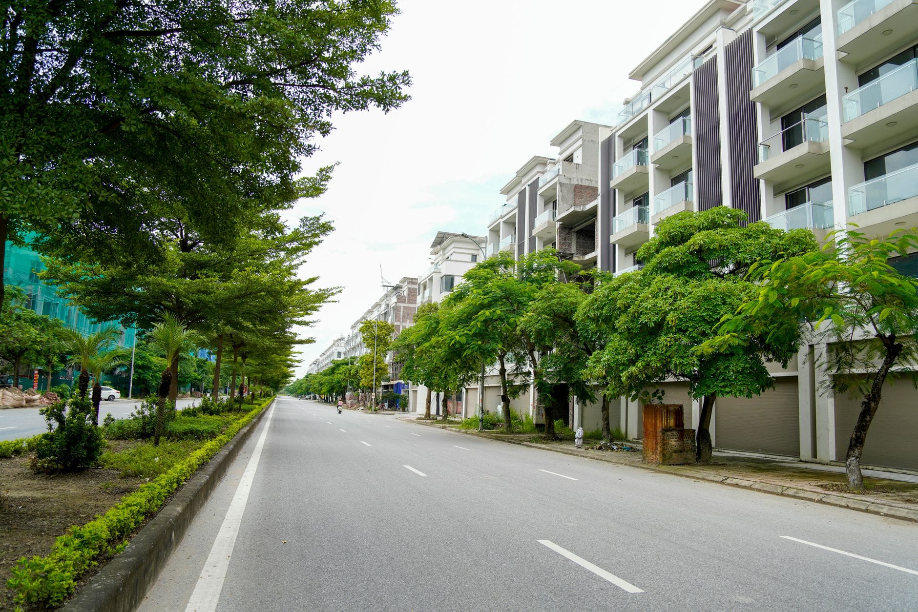 ถนนบูเลอวาร์ดกว้างในดานังพร้อมอาคารสมัยใหม่ความสูงปานกลางและแถวต้นไม้เขียวชะอุ่มริมถนนที่เงียบสงบและสะอาด