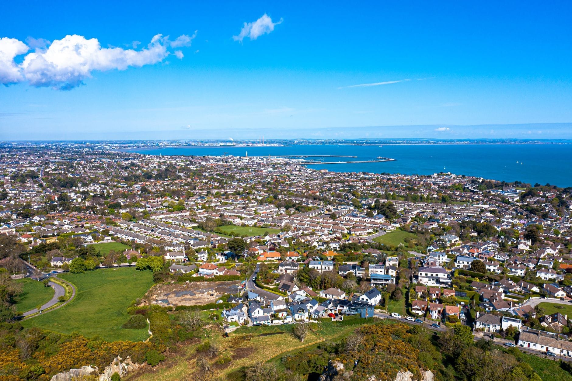 ภาพมุมสูงของ Dalkey และ Killiney เห็นชายฝั่ง สวนเขียวขจี หลังคาบ้าน และอ่าวดับลินใต้อากาศฟ้าใส