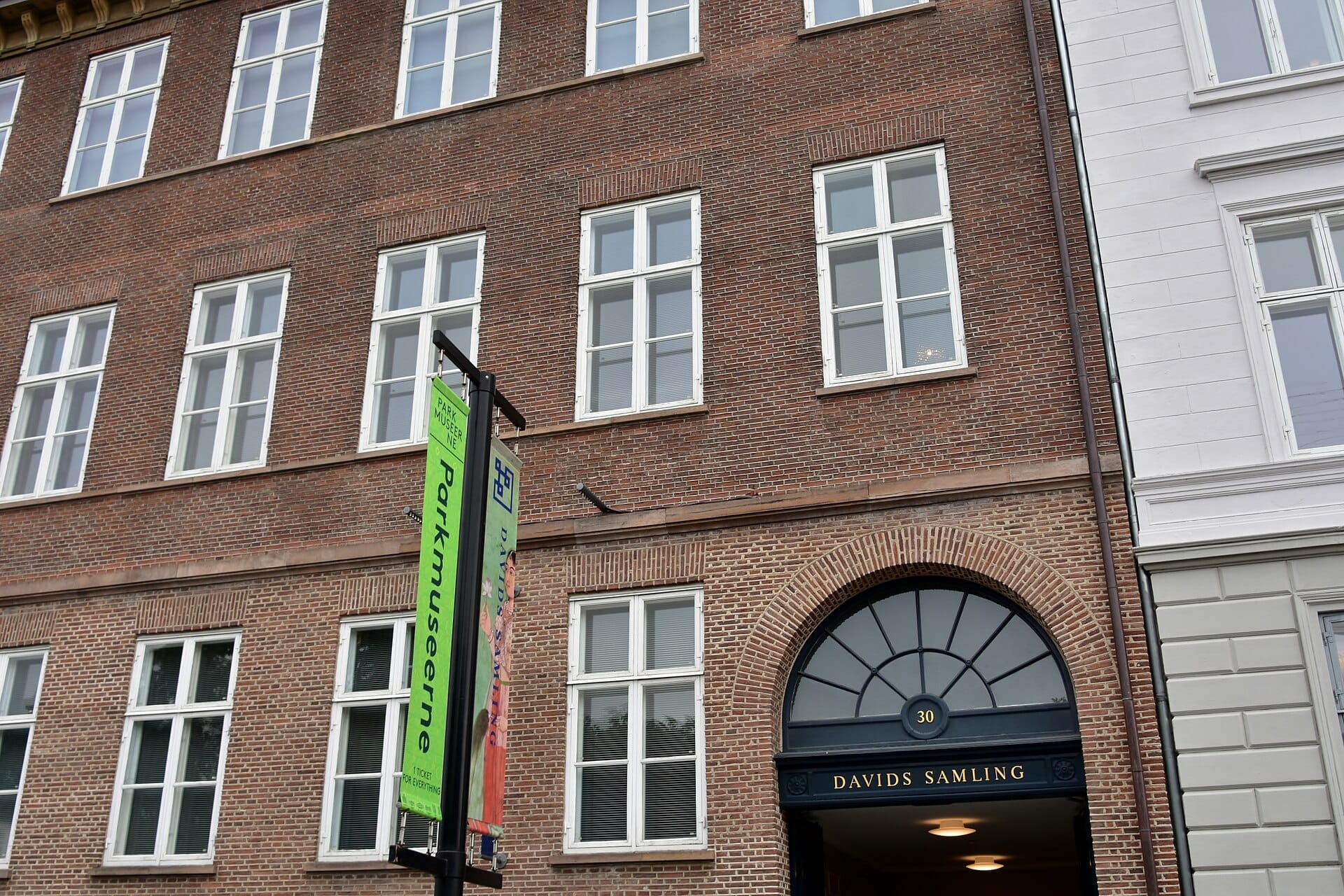 Facciata della David Collection a Copenaghen con esterno in mattoni rossi, ingresso ad arco e striscioni del Parkmuseerne in una giornata nuvolosa.