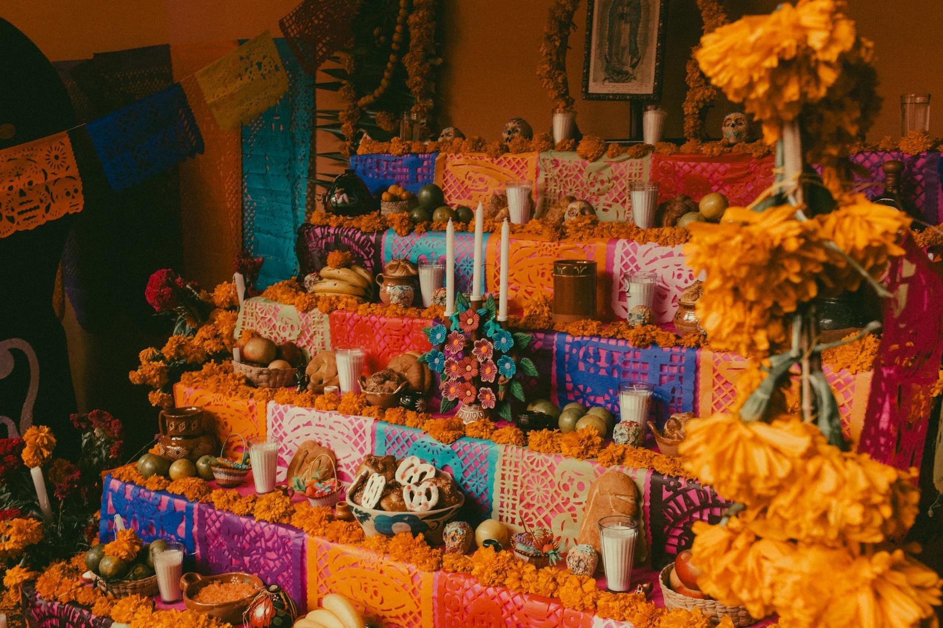 Altar tradicional de vários níveis do Día de Muertos com velas, calêndulas, comida, caveiras de açúcar e colorido papel picado na Cidade do México.
