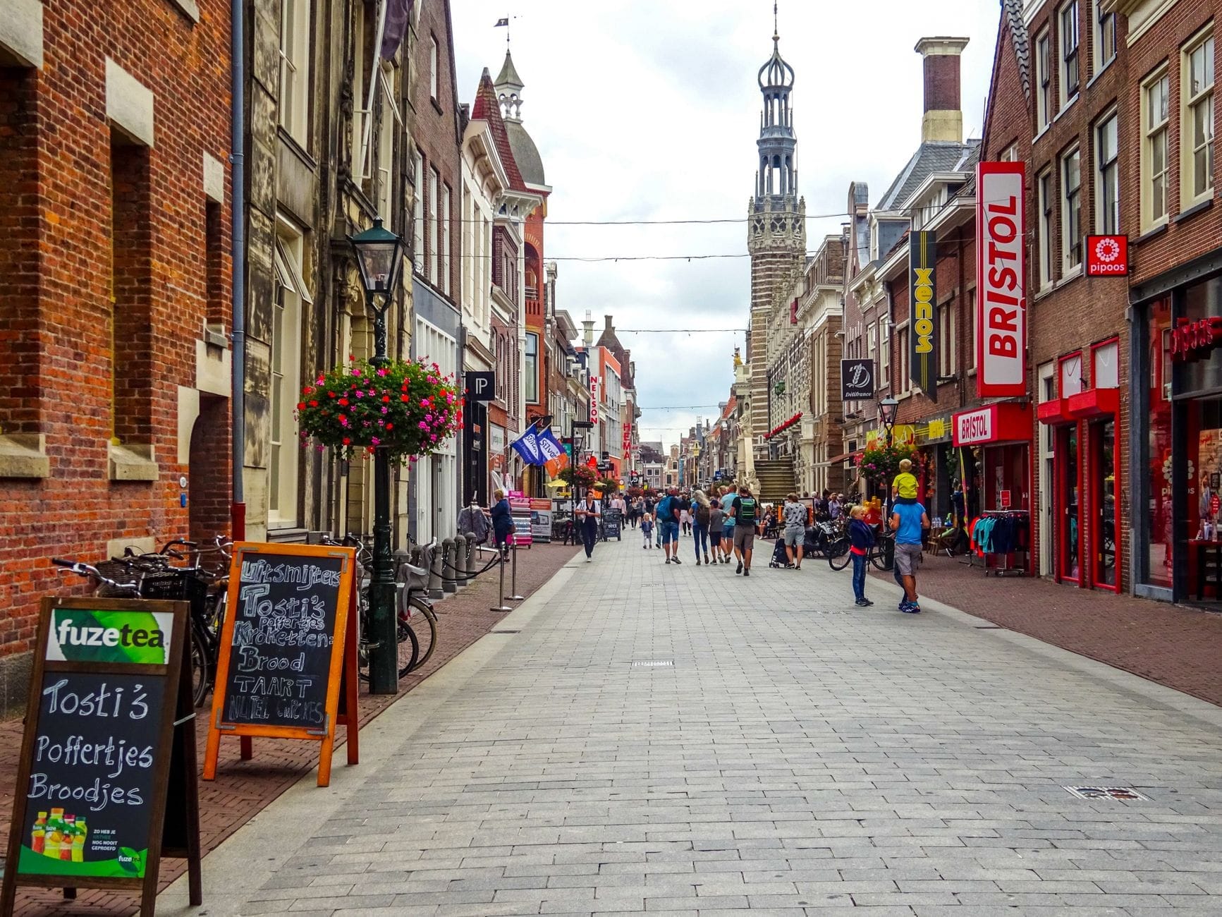 Phố đi bộ nhộn nhịp ở Amsterdam với các cửa hàng, quán cà phê, xe đạp và người đi bộ dưới những công trình kiến trúc lịch sử Hà Lan.