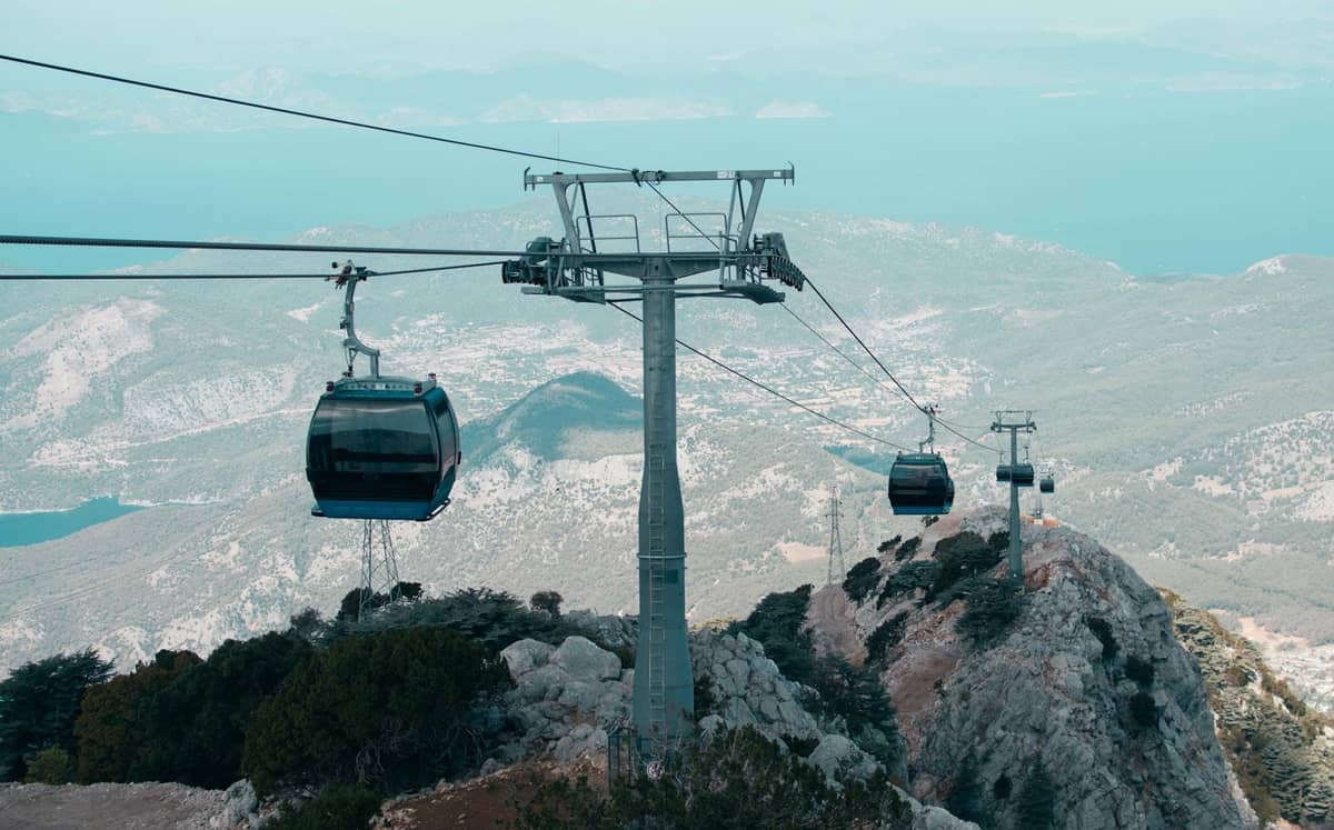 Cable cars ascending over mountainous landscape with views of sea and rugged terrain near Antalya, ideal for adventure and unique experiences.