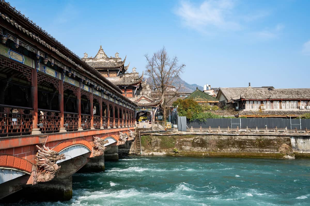 Landschaftsblick auf die verzierte überdachte Brücke und den reißenden Fluss in Dujiangyan – das antike Bewässerungssystem nahe Chengdu und eines der beliebtesten Ausflugsziele.