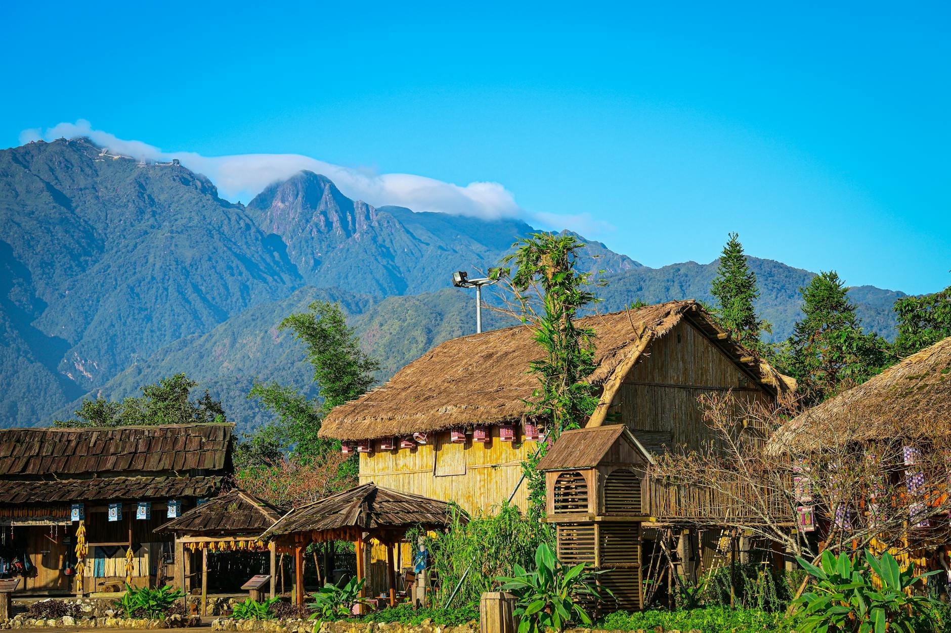Những tòa nhà gỗ truyền thống với mái tranh trước những ngọn núi đá vôi hùng vĩ gần Chiang Dao, miền bắc Thái Lan dưới bầu trời xanh trong.