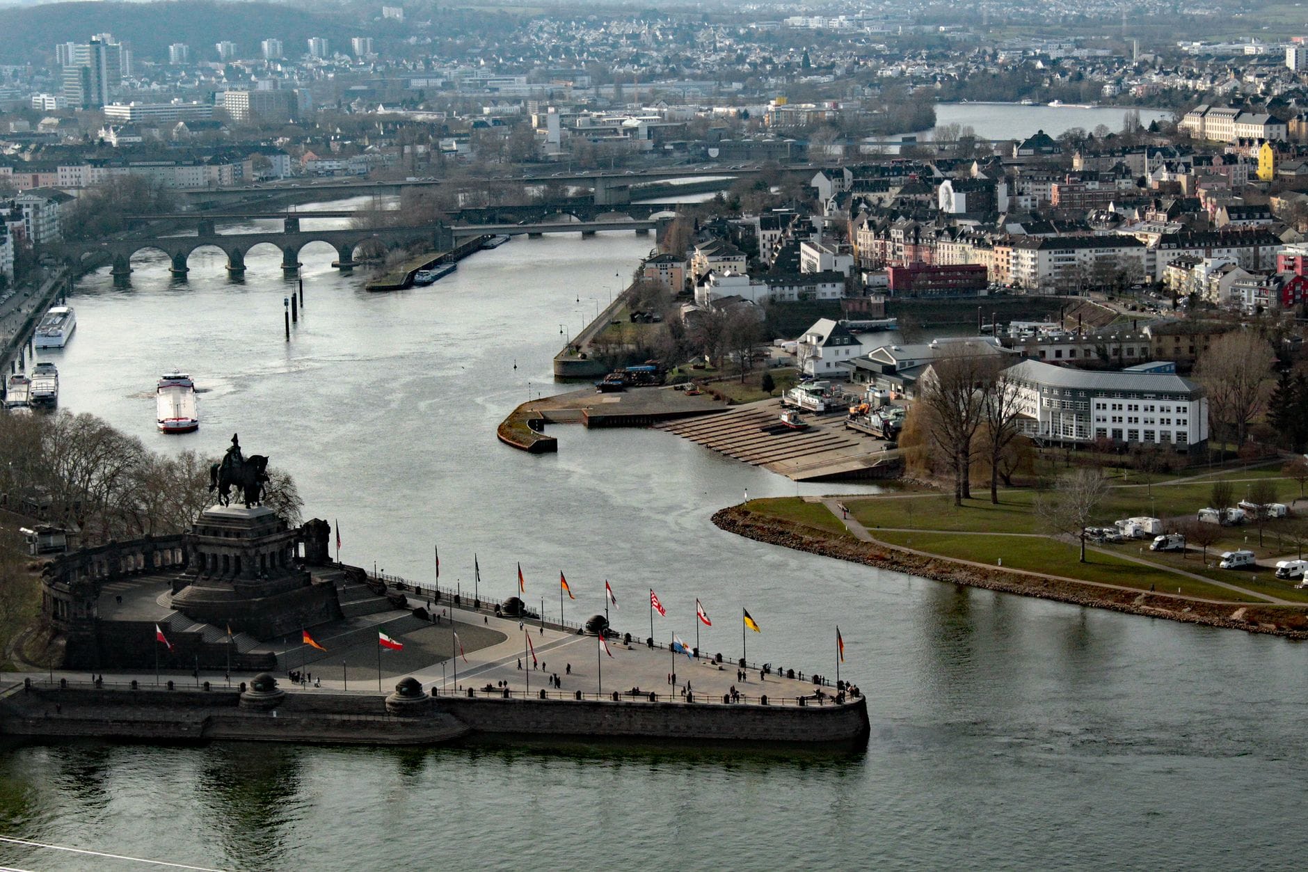 มุมมองทางอากาศของ Deutsches Eck ใน Koblenz จุดที่แม่น้ำ Moselle บรรจบกับ Rhine พร้อมทัศนียภาพของเมือง สะพาน และแม่น้ำ