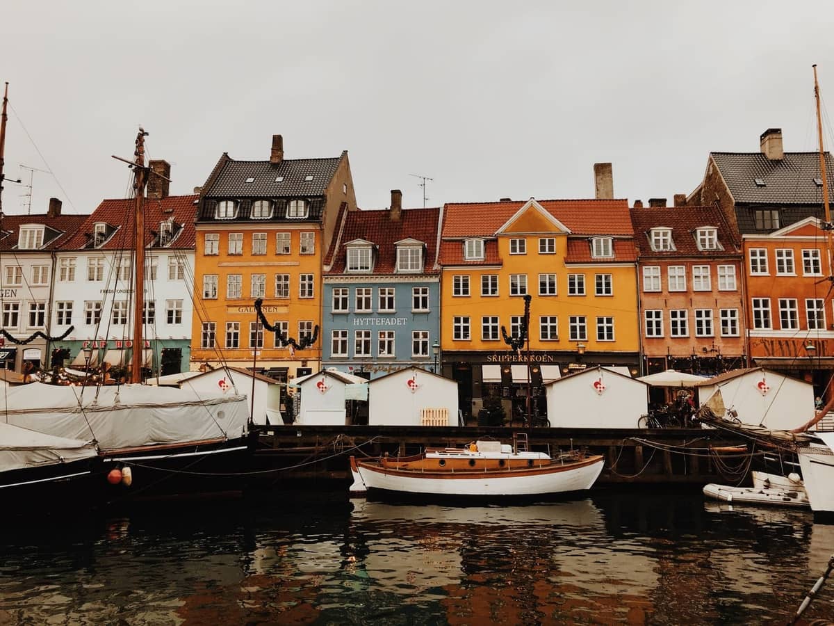 Bunte historische Häuser und Boote entlang der ikonischen Uferpromenade Nyhavn in Kopenhagen an einem bewölkten Tag.
