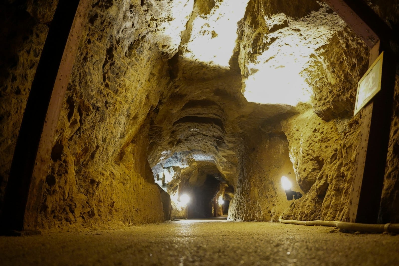 Vista bien iluminada dentro de un túnel con paredes texturizadas y luces montadas a lo largo del pasaje, evocando sitios históricos de guerra subterráneos.