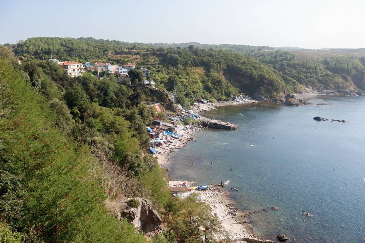 İstanbul yakınlarındaki Karadeniz kıyısında evleri, kumlu plajı, kayalık sahili ve yeşil tepeleriyle küçük bir kıyı köyünün havadan görünümü.