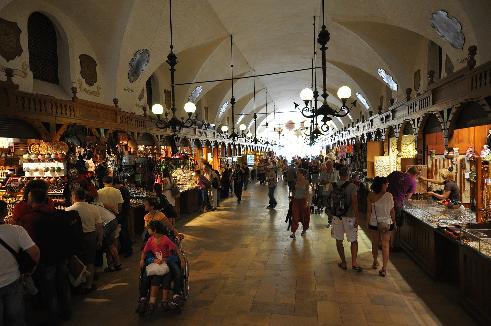 วิวภายในของ Kraków อาคาร Sukiennice ที่มีเพดานโค้ง แผงตลาด และผู้คนกำลังช้อปปิ้ง ตั้งอยู่ในเมืองเก่าที่ได้รับการขึ้นทะเบียนโดย UNESCO