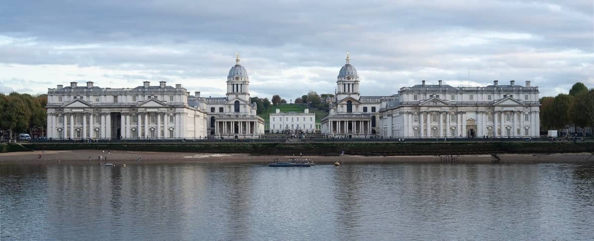 Vista panorâmica do Old Royal Naval College do outro lado do Tâmisa sob um céu nublado, Património Mundial da UNESCO em Greenwich, Londres.