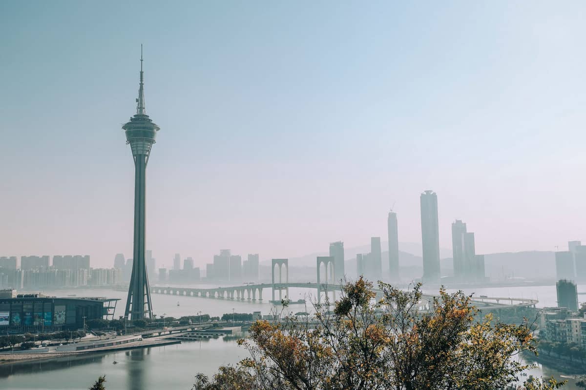 Skyline von Macau mit dem Macau Tower, einer Brücke und modernen Hochhäusern entlang der Uferpromenade an einem klaren Tag