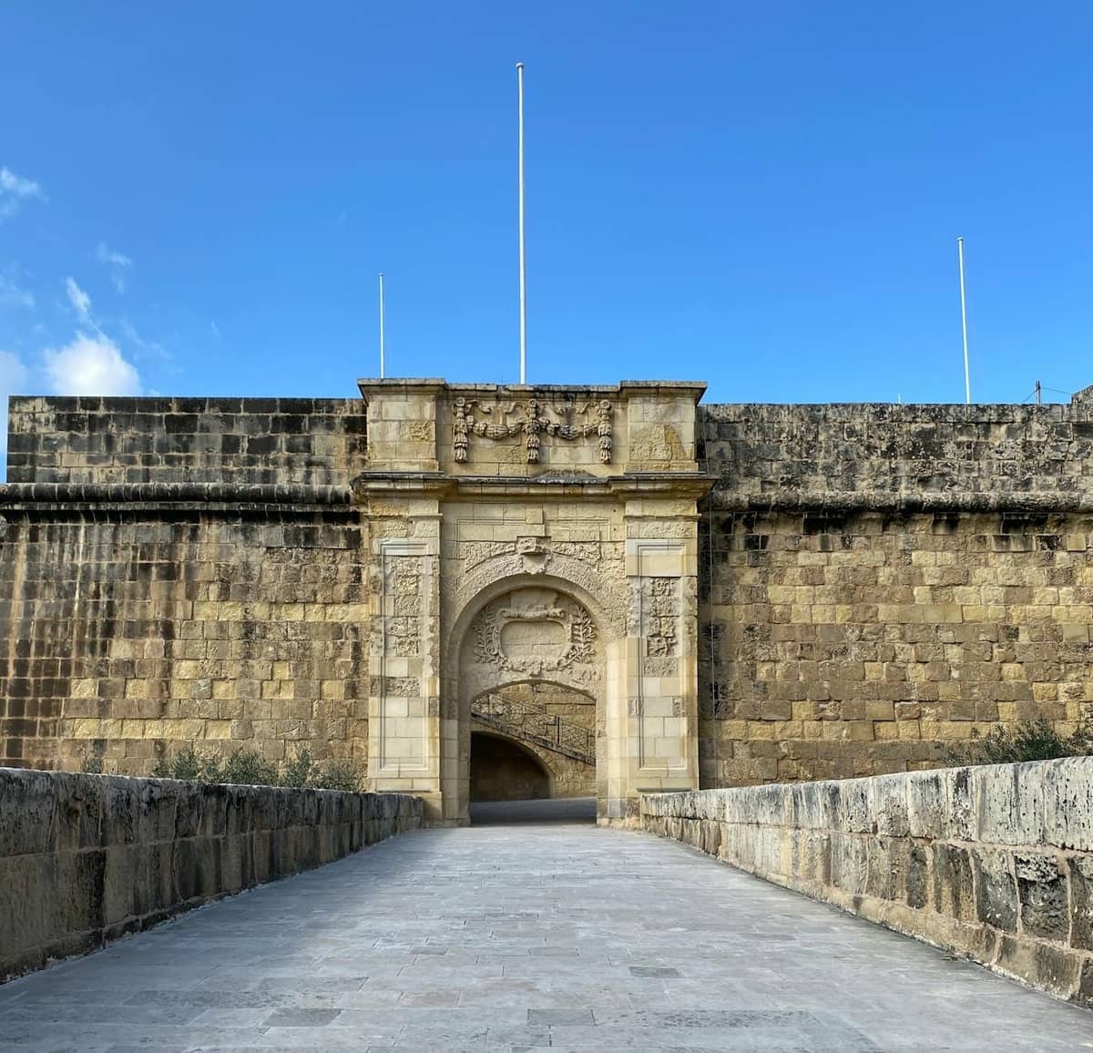Steinernes Tor der alten Zitadelle von Mdina in Malta, mit hohen Verteidigungsmauern und blauem Himmel.