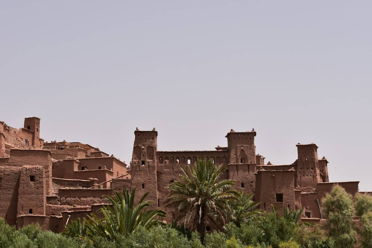 วิวเมืองโบราณอิฐโคลน Ait Benhaddou ที่มีต้นปาล์มล้อมรอบและท้องฟ้าแจ่มใส ใกล้มาราเกช—หนึ่งในทริปวันเดียวห้ามพลาดจากตัวเมือง