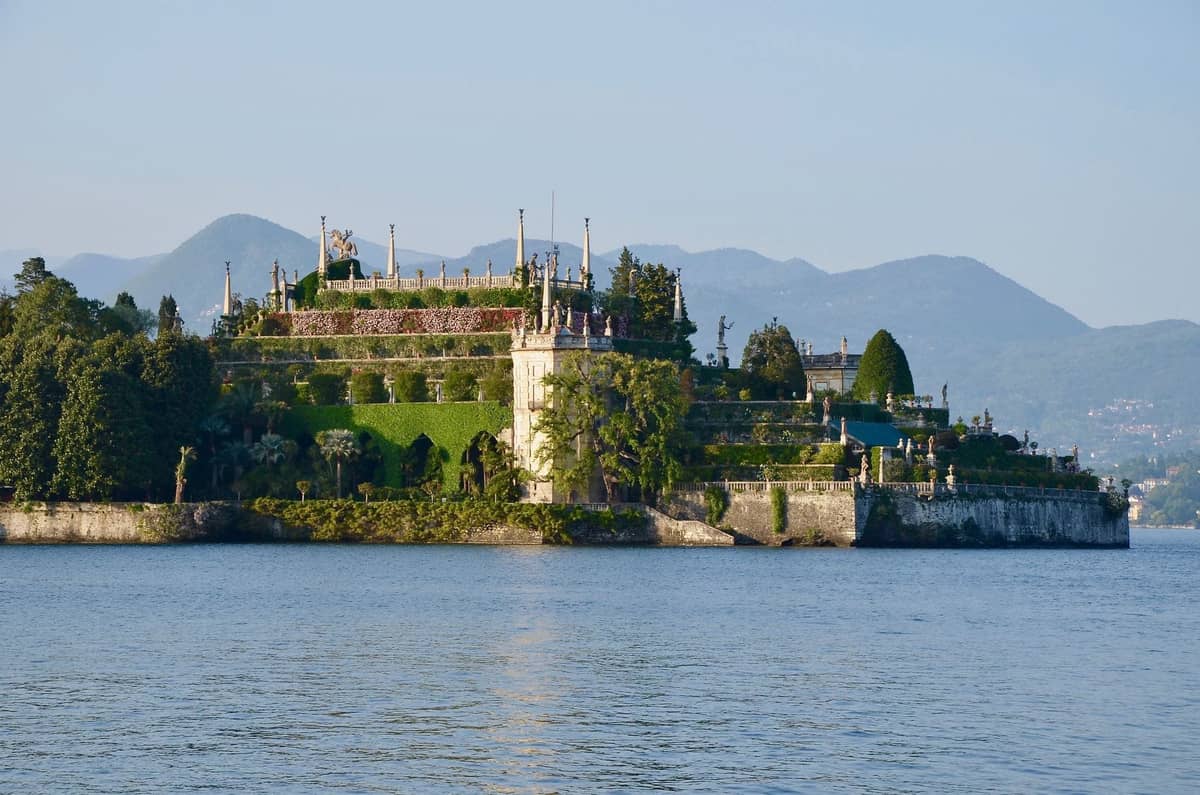 A clear view of Isola Bella on Lake Maggiore, featuring Palazzo Borromeo and terraced baroque gardens, with mountains in the background.