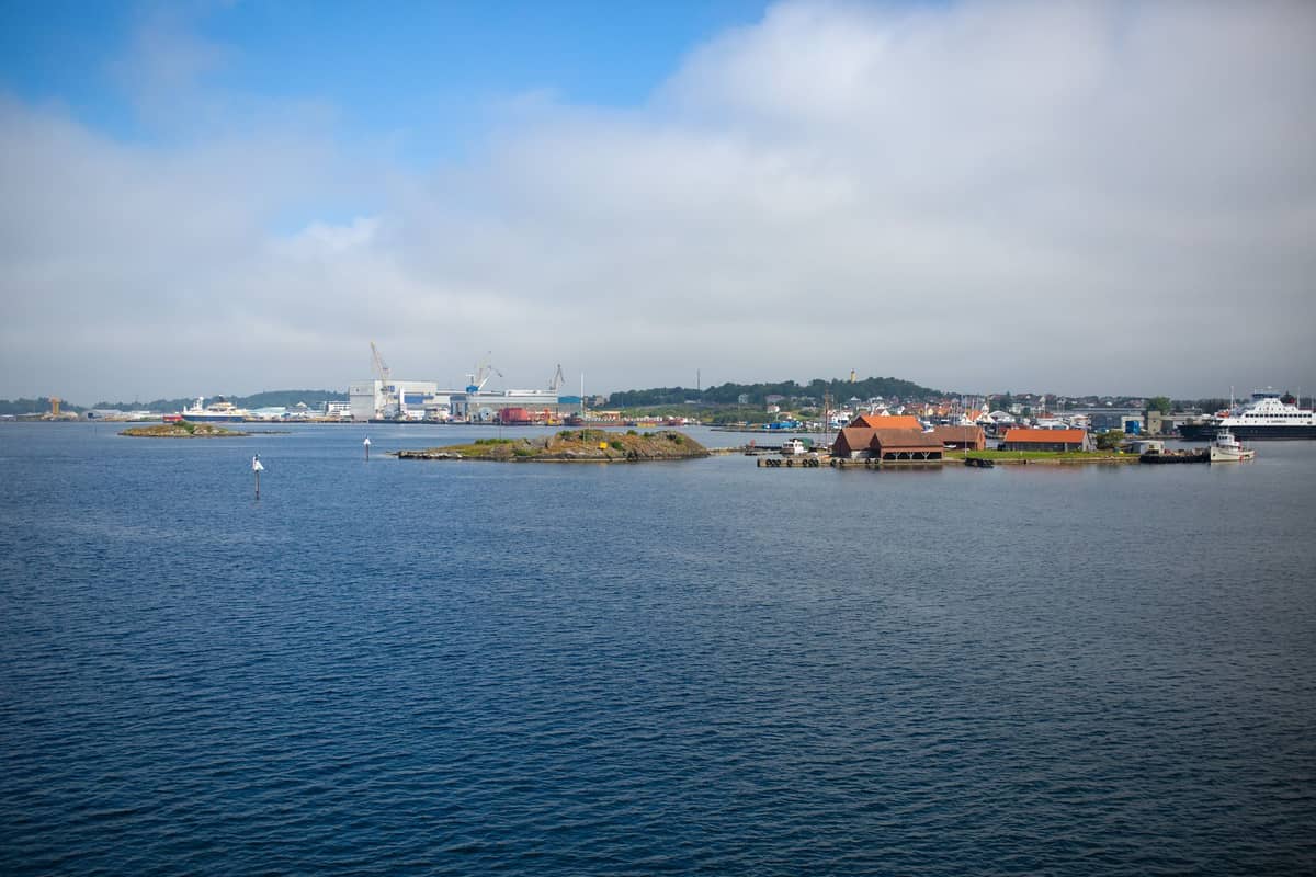 เกาะเล็กๆ ที่มีอาคารหลังคาสีแดงใน Oslofjord โดยมีเมืองและท่าเรือของ Oslo เป็นฉากหลังใต้ท้องฟ้าสีฟ้า