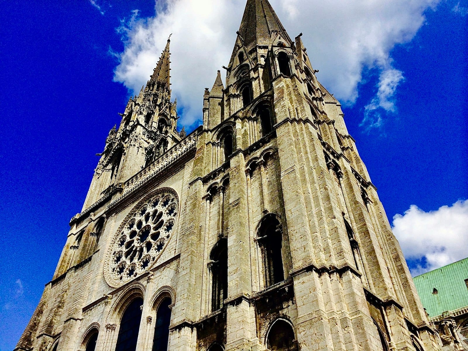 Chartres Katedrali'nin mavi gökyüzü ve bulutlar önünde iki gotik kulesiyle dramatik yukarı bakış açısından görünümü.