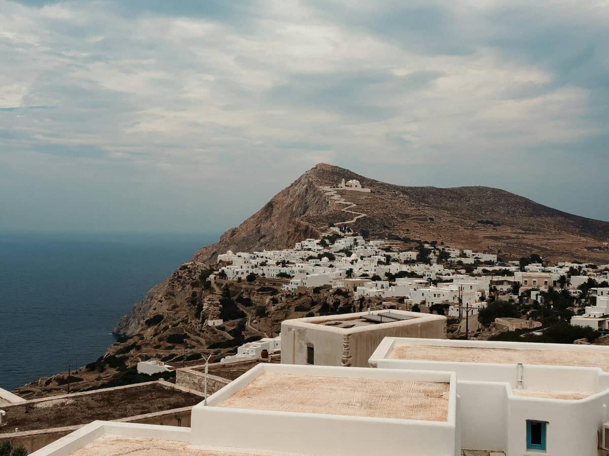 Malerischer Blick auf eine Insel der Kykladen mit weiß getünchten Gebäuden auf einem Hügel mit Meerblick, typisch für Ios oder Folegandros in der Nähe von Santorin.