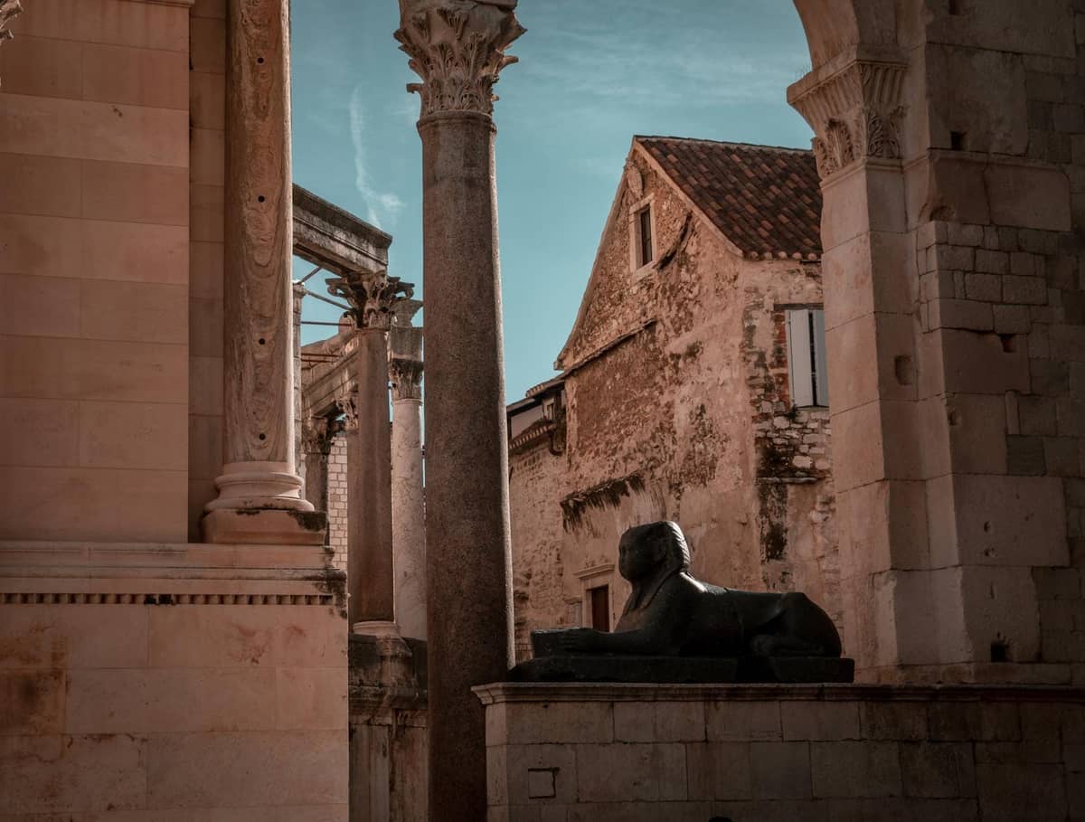 Antike Steinsäulen, Bögen und eine schwarze Granitsphinx in den historischen Ruinen des Diokletianspalasts in Split, Kroatien.