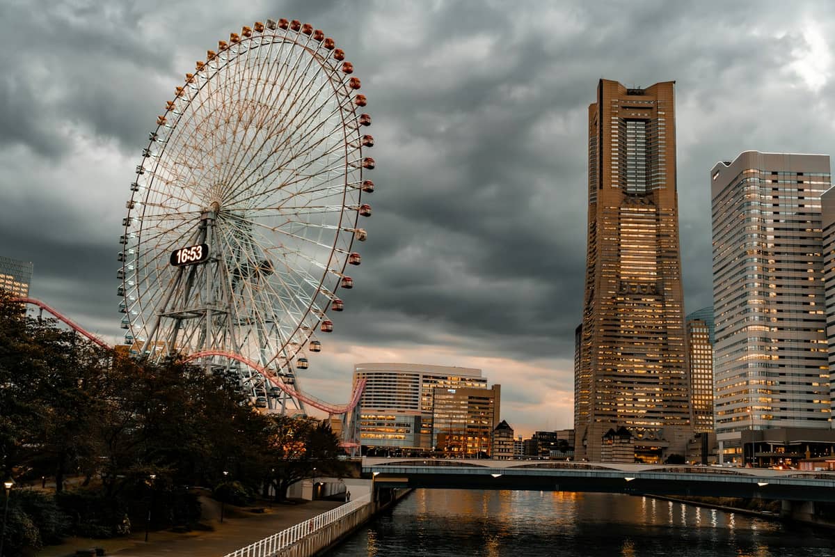 Yokohama waterfront with Cosmo Clock 21 Ferris wheel and Landmark Tower under dramatic cloudy sky.