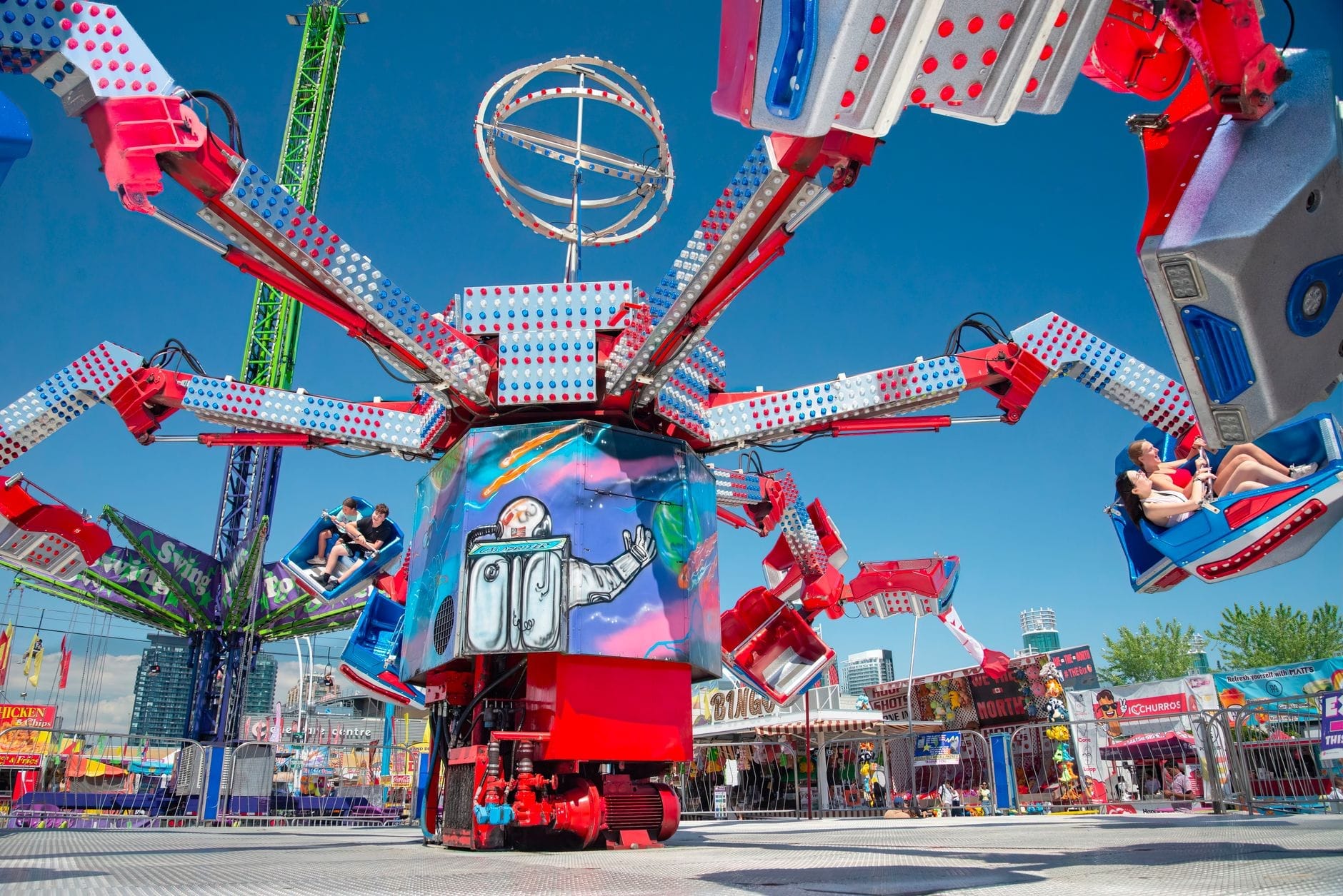 Manège de parc d'attractions vif et coloré avec des personnes assises dans des voitures tournantes lors d'une fête foraine en plein air par une journée ensoleillée.