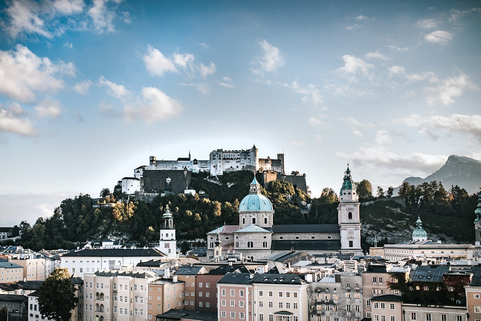 Vista del casco antiguo de Salzburgo con la fortaleza Hohensalzburg en la colina y cúpulas de iglesias barrocas en primer plano.