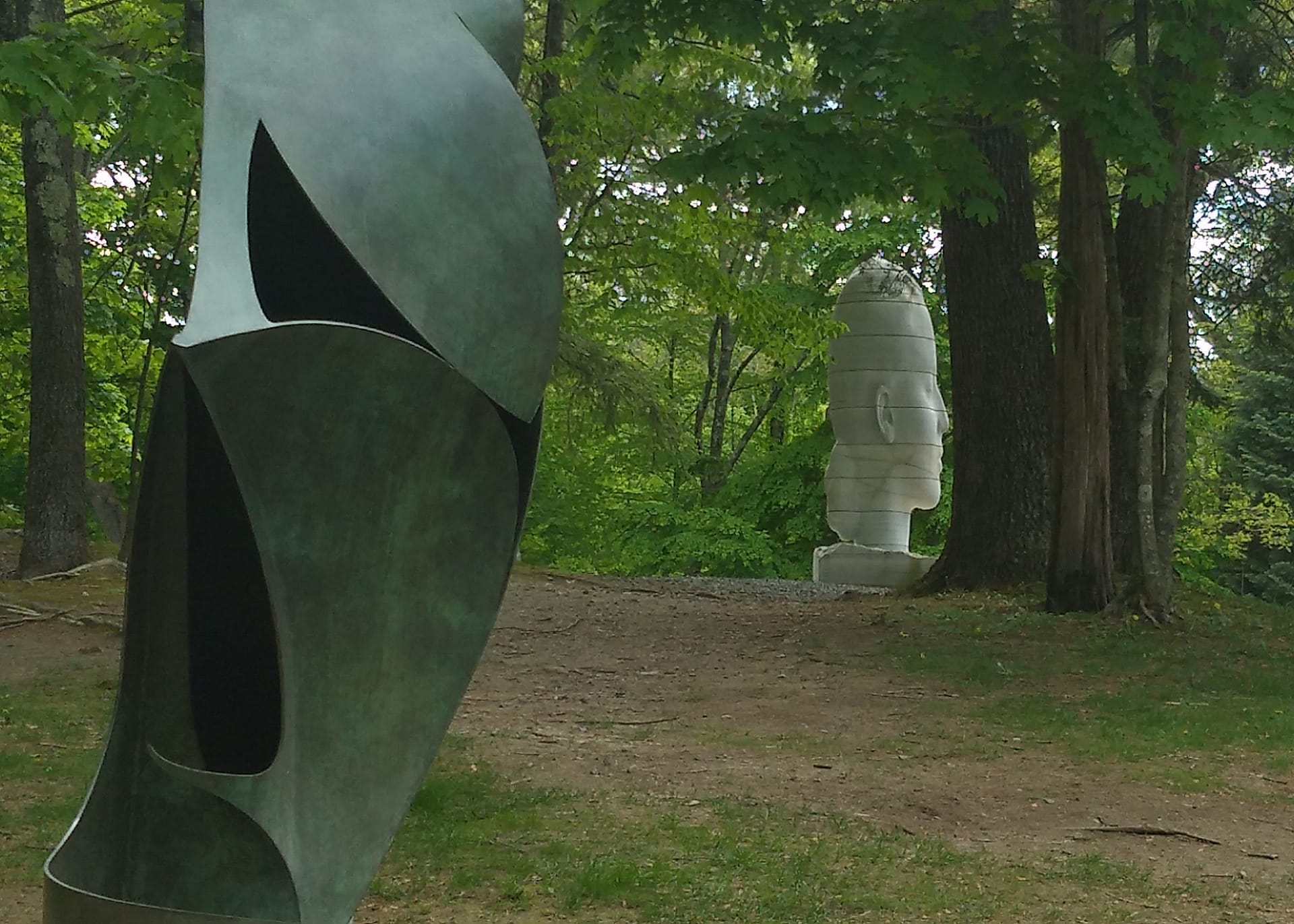 Sculture astratte in metallo e pietra tra alberi alti e prati verdi al deCordova Sculpture Park and Museum a Lincoln, Massachusetts.