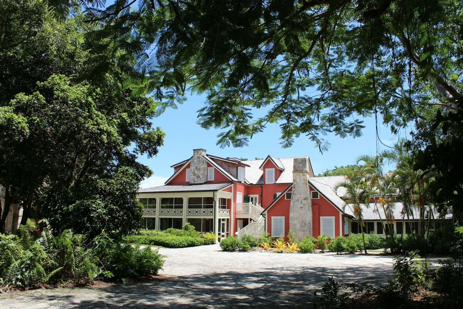 Storico edificio degli anni Venti, rosso e bianco, alla Deering Estate, circondato da alberi lussureggianti sotto un cielo azzurro limpido, che evoca il fascino naturale nascosto di Miami.