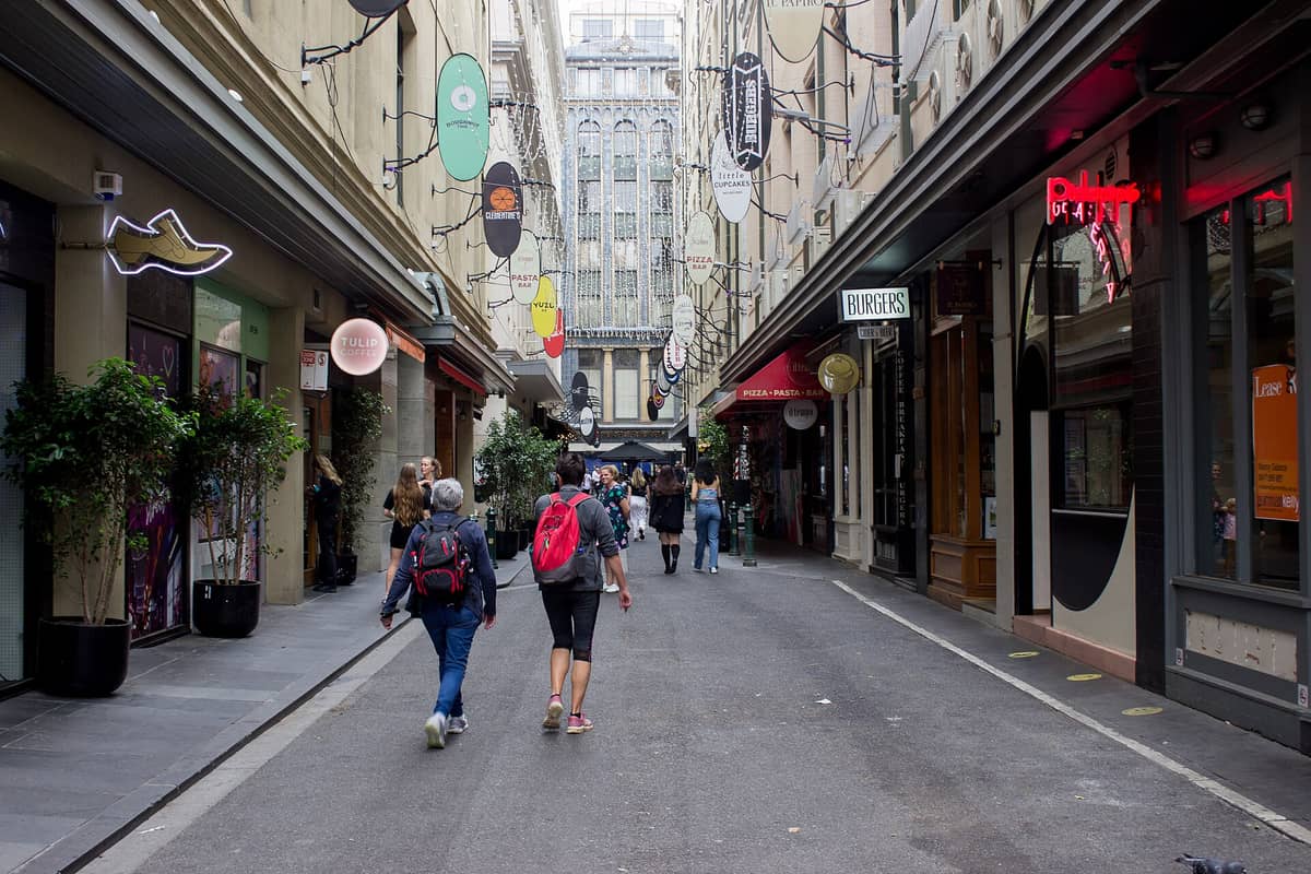 Degraves Street en Melbourne con sus animados cafés, los característicos carteles colgantes de las tiendas y personas paseando por un angosto y atmosférico callejón.