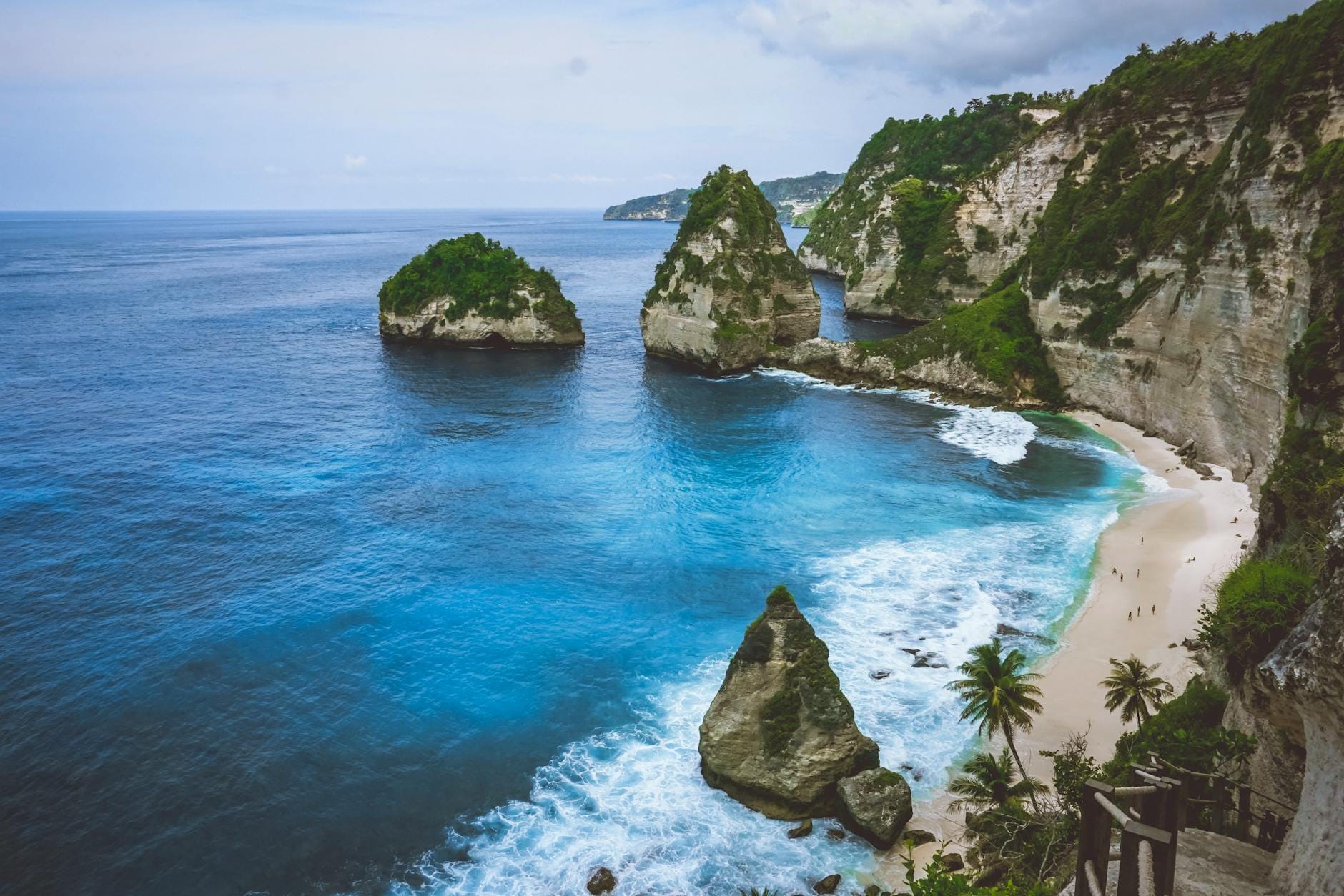 Sabbia bianca e acqua turchese a Diamond Beach, Nusa Penida, Bali, con pinnacole calcaree che si innalzano dalla riva