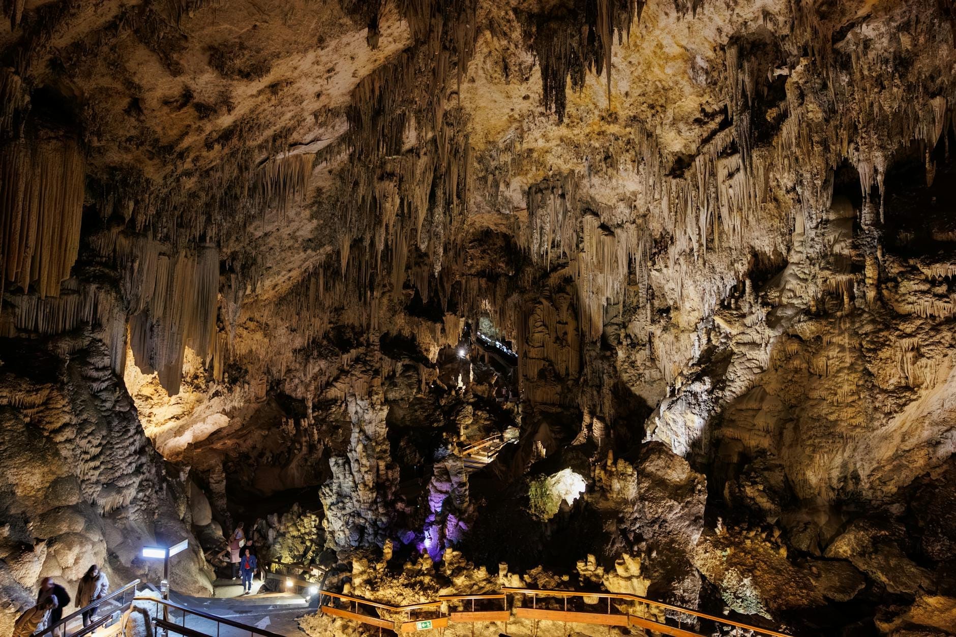 Vista ampia dell'interno spettacolare della Grotta Diktea con stalattiti, passerelle illuminate, formazioni rocciose selvagge e visitatori che ammirano l'incantevole paesaggio sotterraneo.