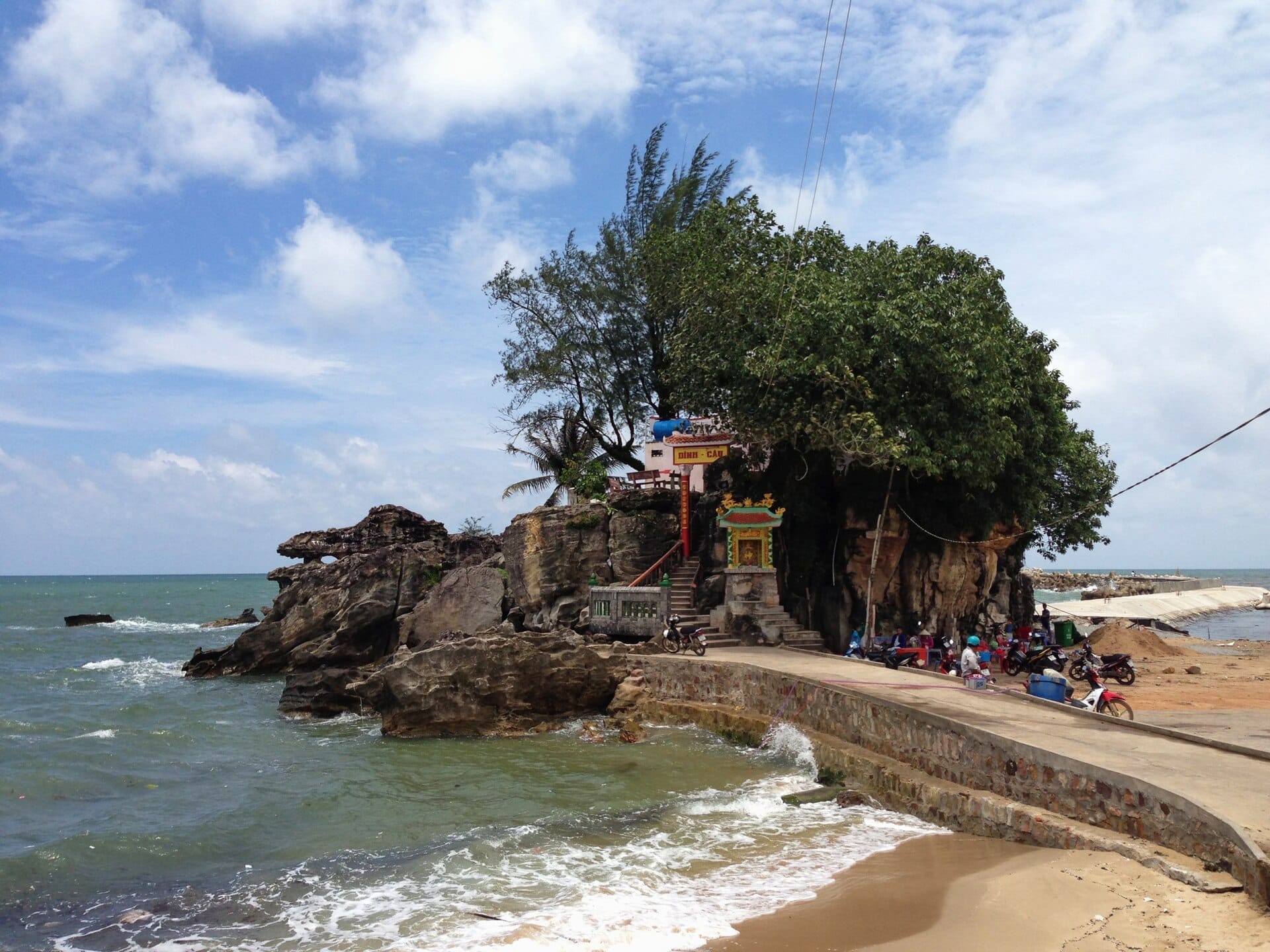 Il tempio Dinh Cau sullo sperone roccioso affacciato sul mare a Phu Quoc, con il santuario, le scalinate e le onde che si infrangono sotto