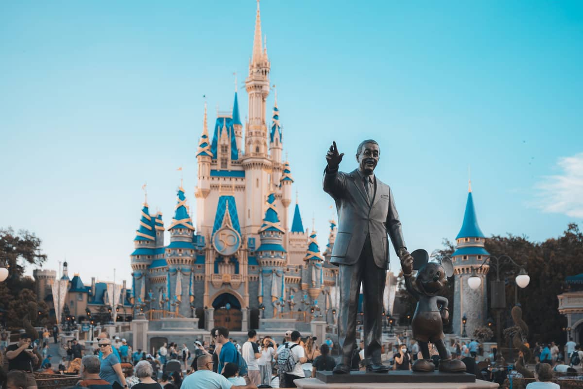Multitud de visitantes frente al Castillo de la Cenicienta con la estatua de Walt Disney y Mickey Mouse en Disney World Orlando