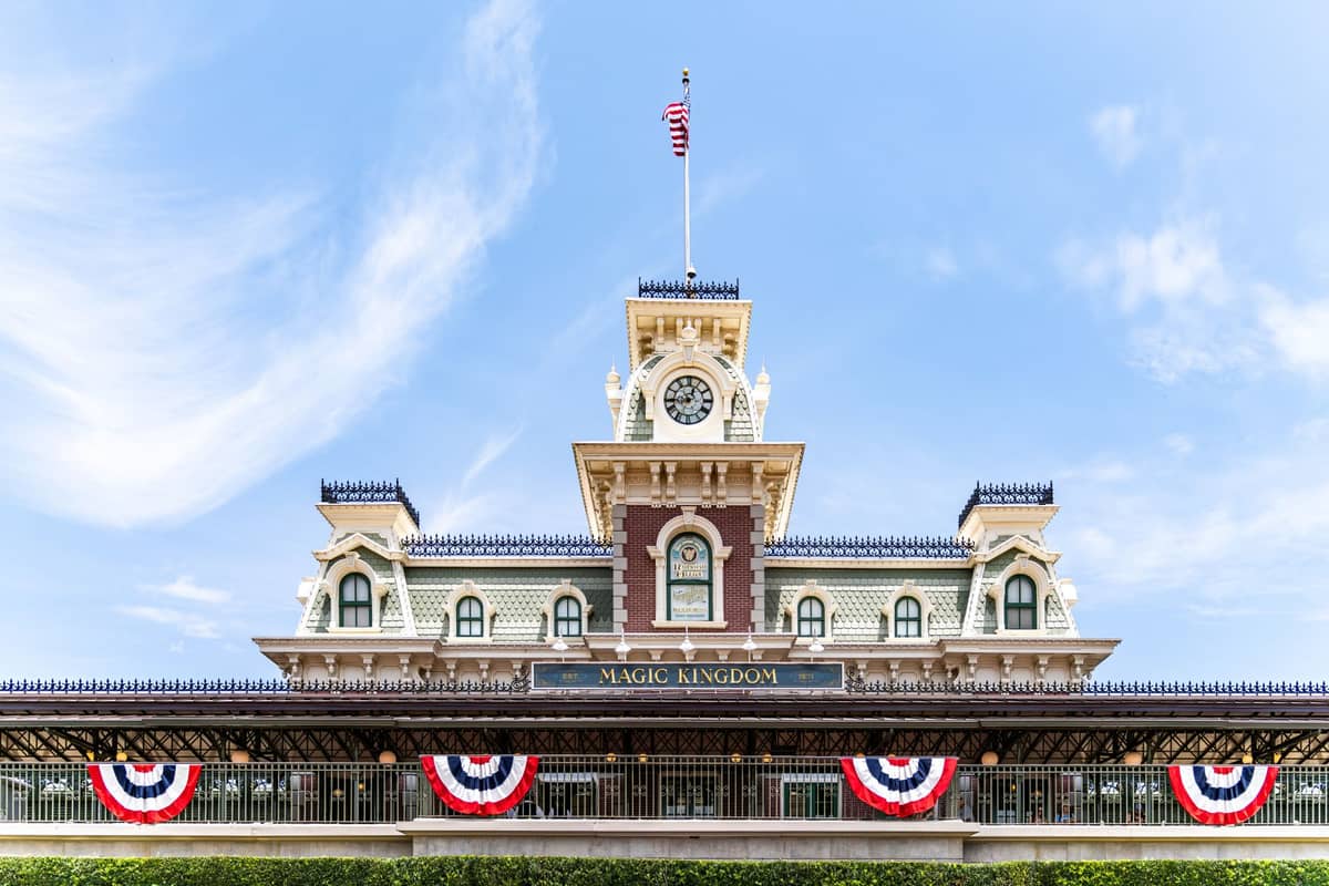 La entrada de Magic Kingdom en Walt Disney World, con la estación de tren de Main Street con una torre de reloj y banderines patrióticos