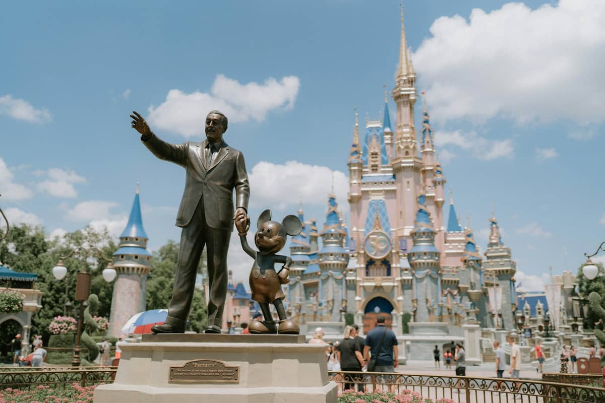 La estatua de Los Socios con Walt Disney y Mickey Mouse frente al Castillo de Cenicienta en Magic Kingdom de Disney World en un día soleado.