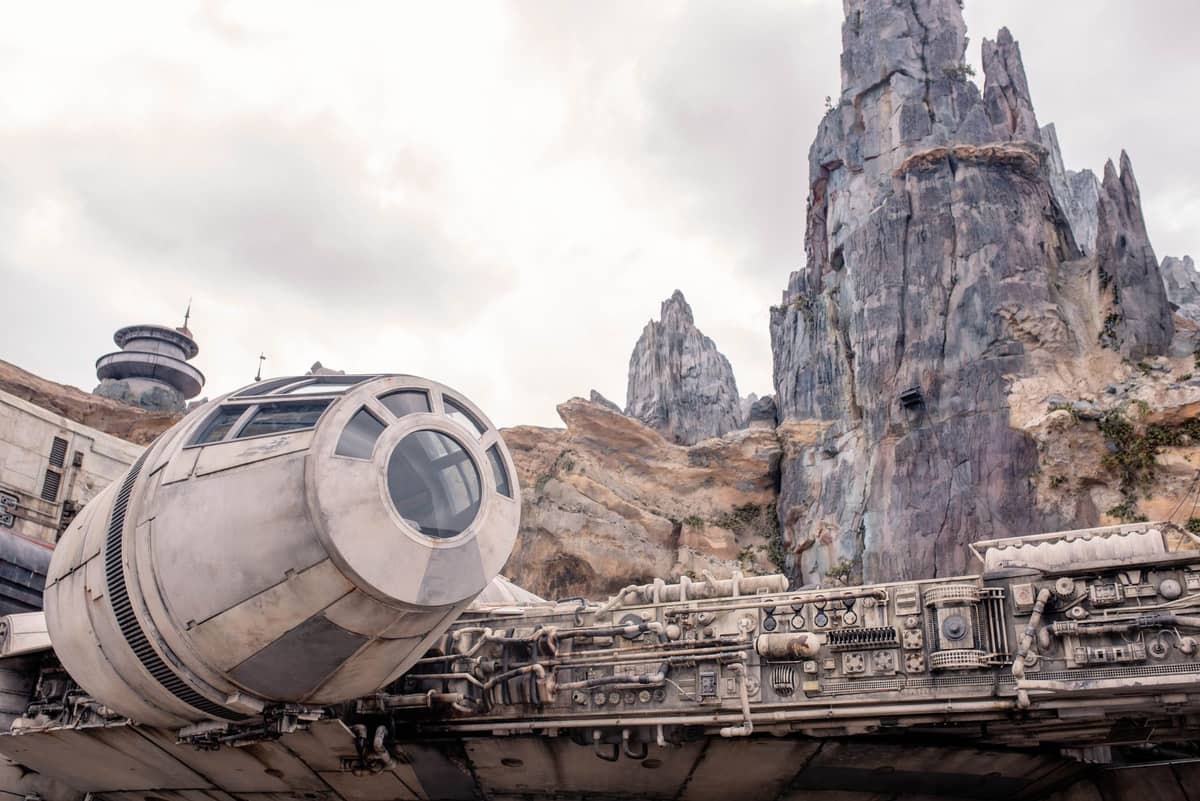 Close-up view of the Millennium Falcon spaceship with Star Wars: Galaxy's Edge rock spires behind it at Disney's Hollywood Studios.