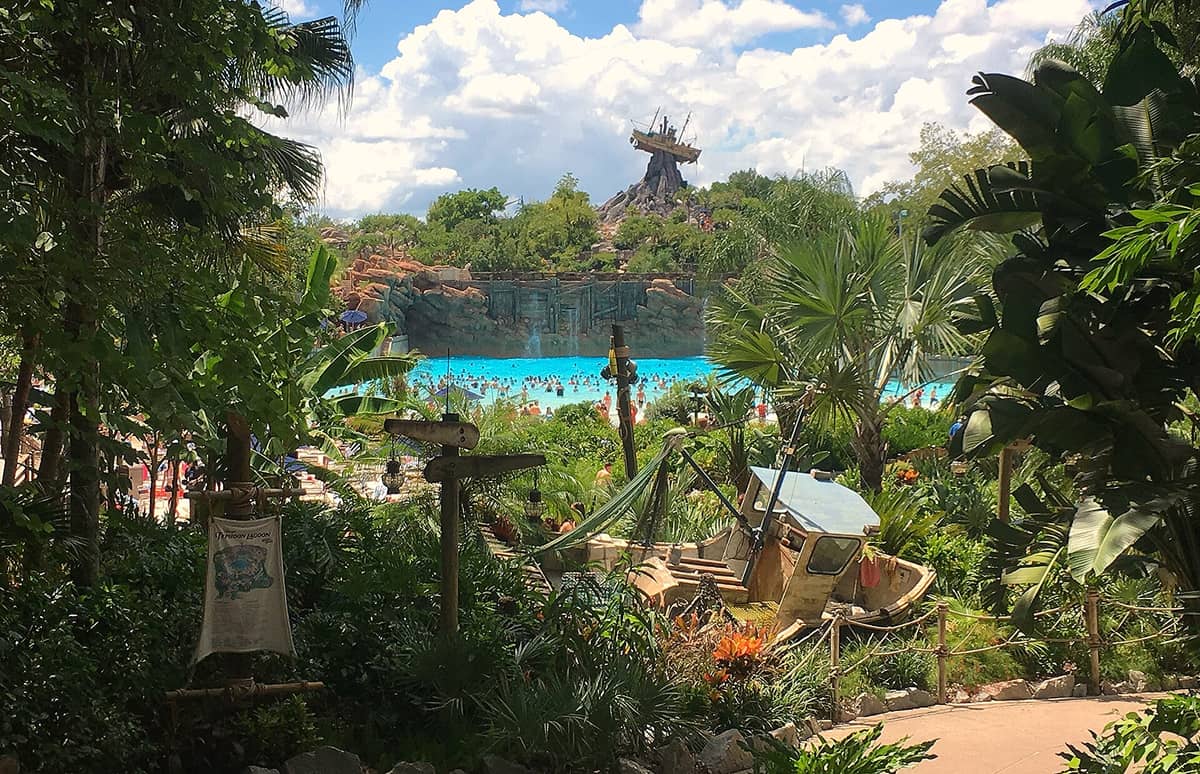 Weitblick auf Disney's Typhoon Lagoon mit dem ikonischen Schiffswrack auf dem Mount Mayday und einem belebten Wellenbad, umgeben von üppiger tropischer Vegetation.