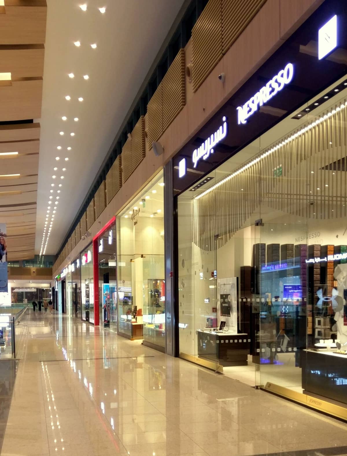 Innenansicht des Einkaufszentrums Doha Festival City mit modernen Ladenfronten, Glaswänden und polierten Böden unter heller Beleuchtung.