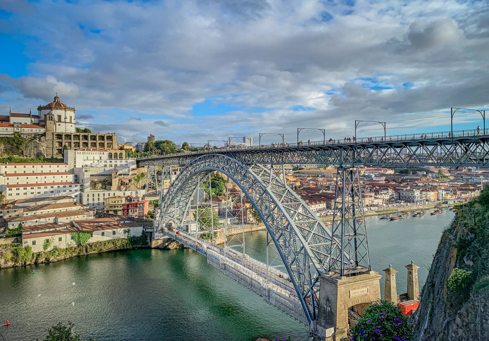 La Ponte Dom Luís I si inarca sul fiume Douro, collegando i colorati edifici storici di Porto e Vila Nova de Gaia sotto un cielo spettacolare.