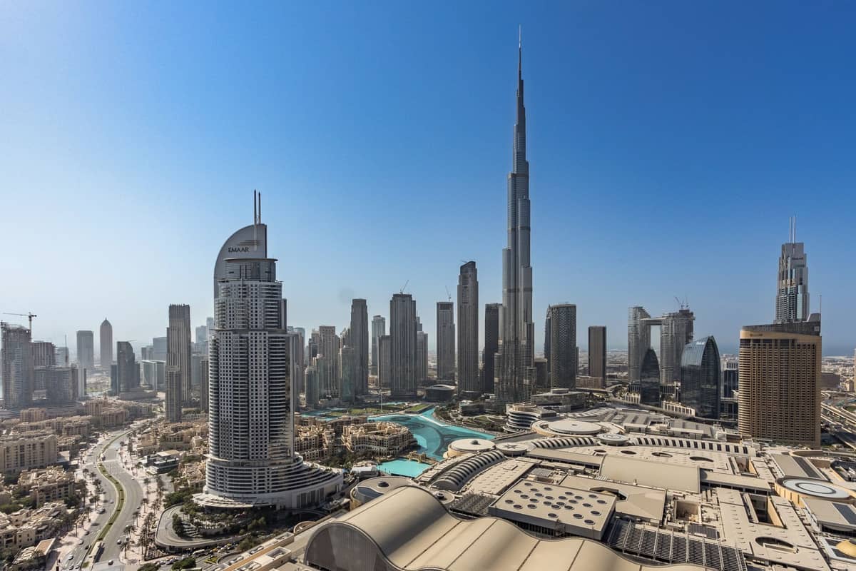 Weitwinkelpanorama der Innenstadt von Dubai bei Tag mit dem Burj Khalifa und den umliegenden Wolkenkratzern unter strahlend blauem Himmel.
