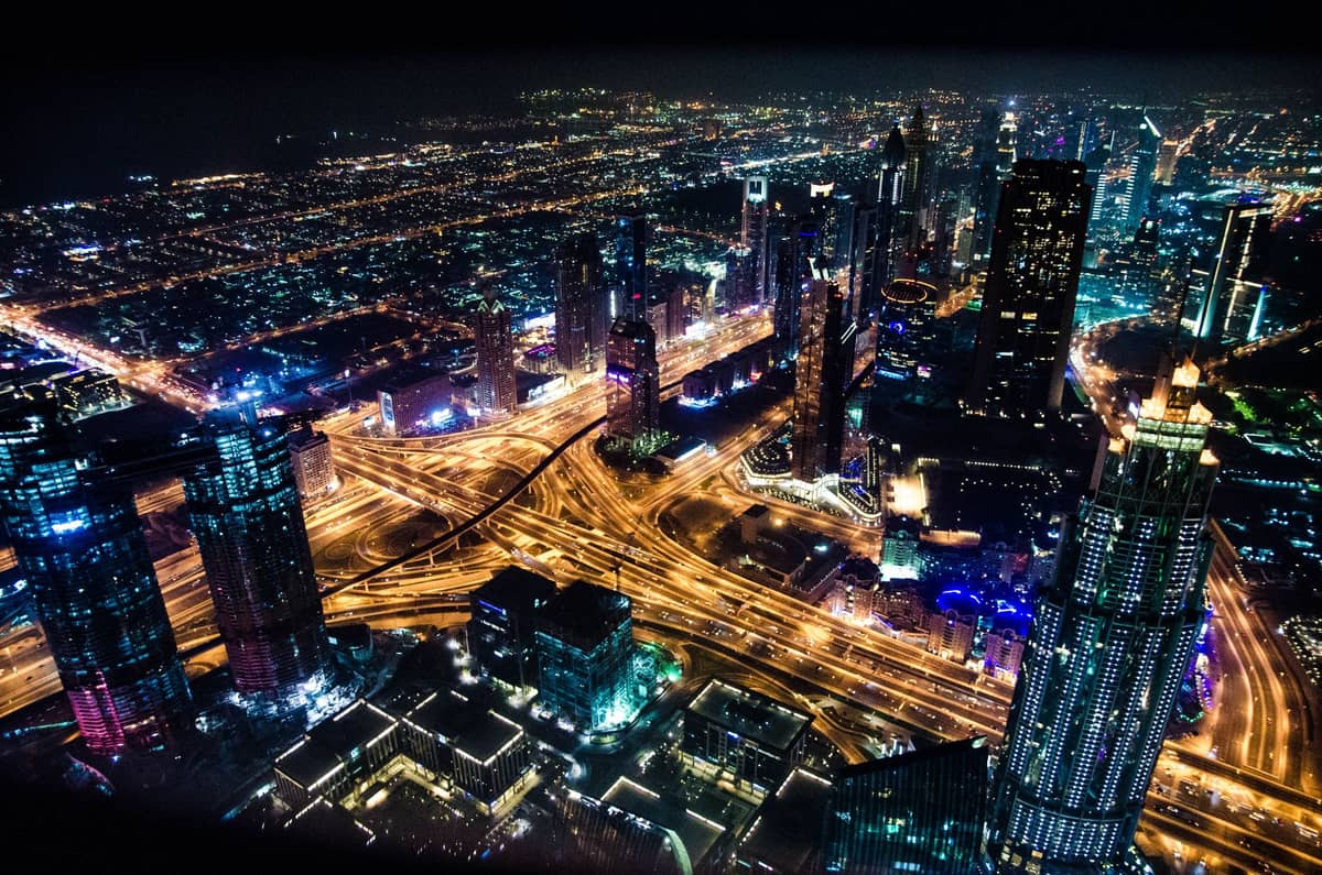 Nächtliche Vogelperspektive auf die beleuchteten Wolkenkratzer und Straßen von Dubai, die die Stadtsilhouette von oben in einer aufregenden Hochaltitudenperspektive zeigt.