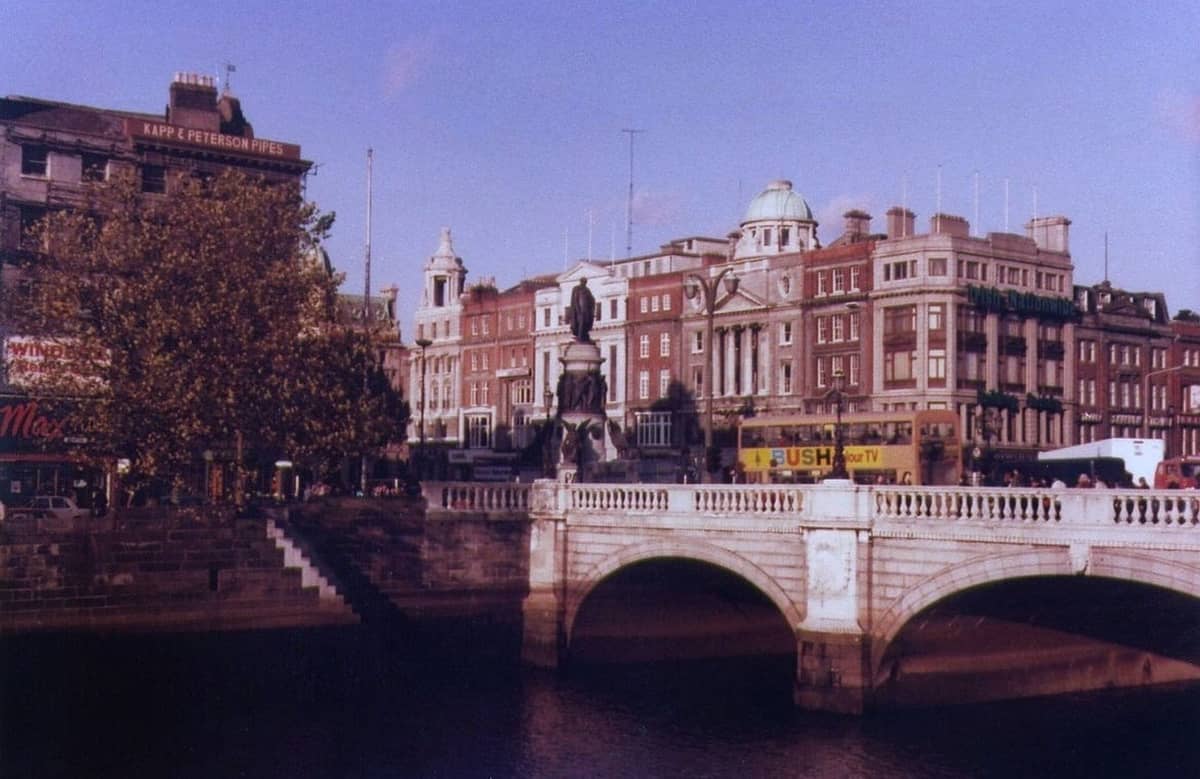 Weitblick auf die O'Connell Bridge und die historischen Gebäude von Dublin unter blauem Himmel, mit dem River Liffey im Vordergrund.