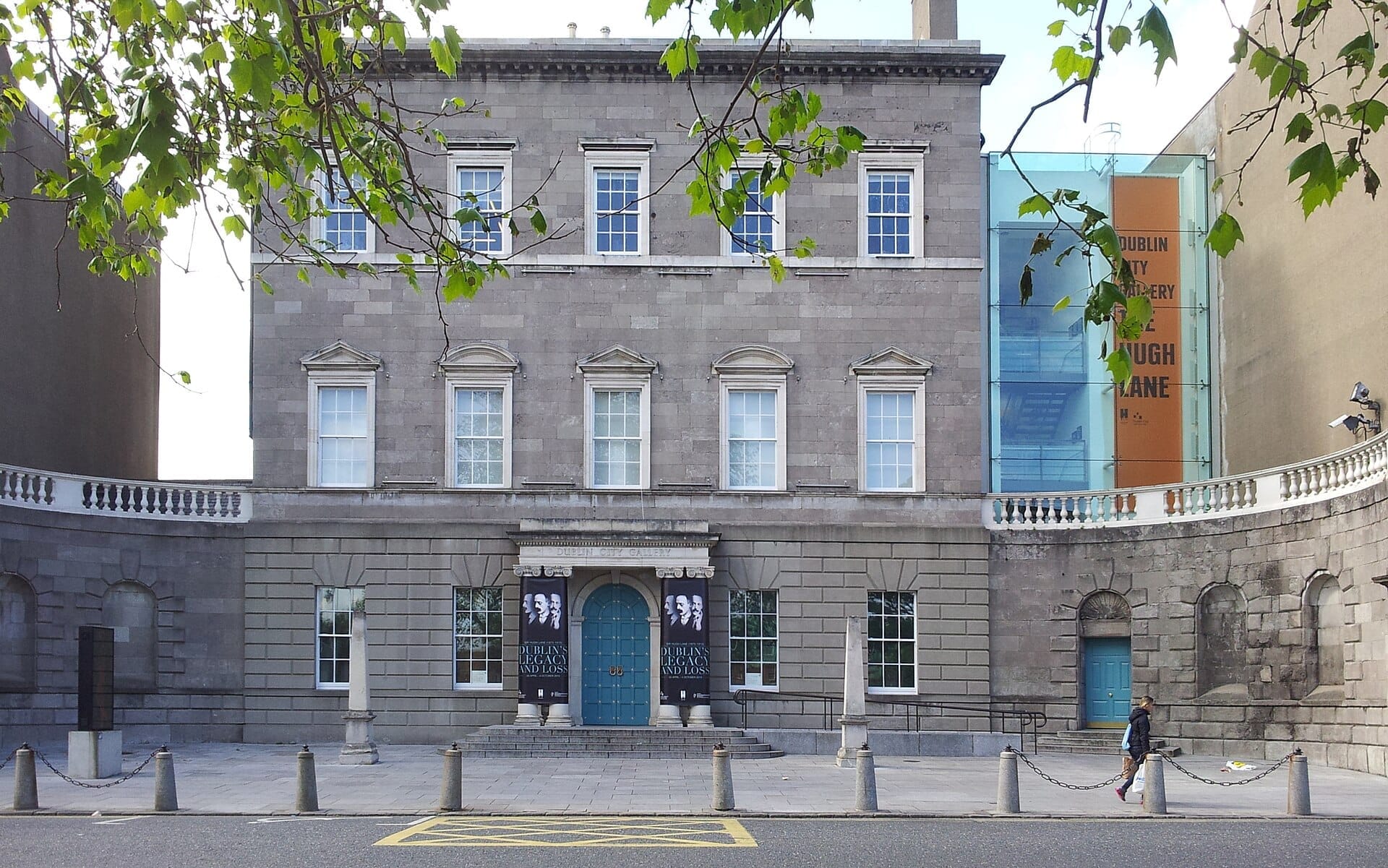 Vista frontale della Dublin City Gallery The Hugh Lane, un maestoso edificio georgiano con facciata in pietra, finestre ad arco e una porta d'ingresso blu.