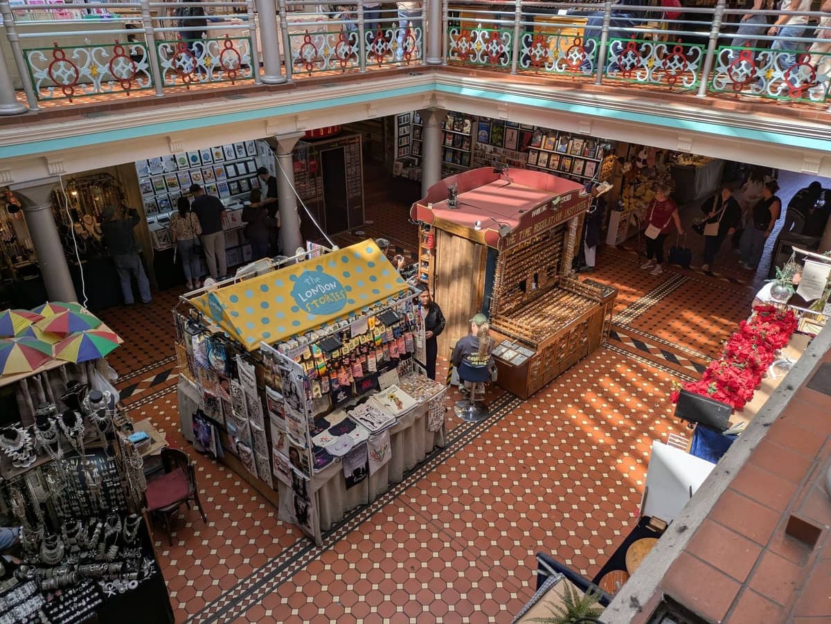Indoor Victorian-style market in Dublin with tiled floor, colorful stalls selling crafts and jewelry, and people browsing on two levels.