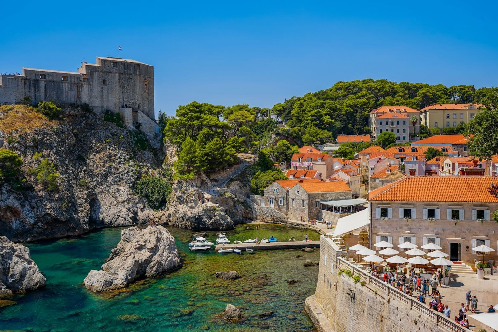 Cảnh tường thành cổ của Dubrovnik với khách du lịch gần Cổng Pile và các quán cà phê ngoài trời, khu vực phổ biến để mua hoặc kích hoạt city pass.