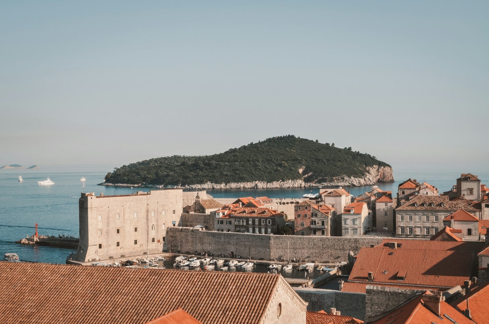 Cảnh thành phố cổ Dubrovnik với đảo Lokrum ở phía sau, nhìn ra biển dưới bầu trời quang đãng.