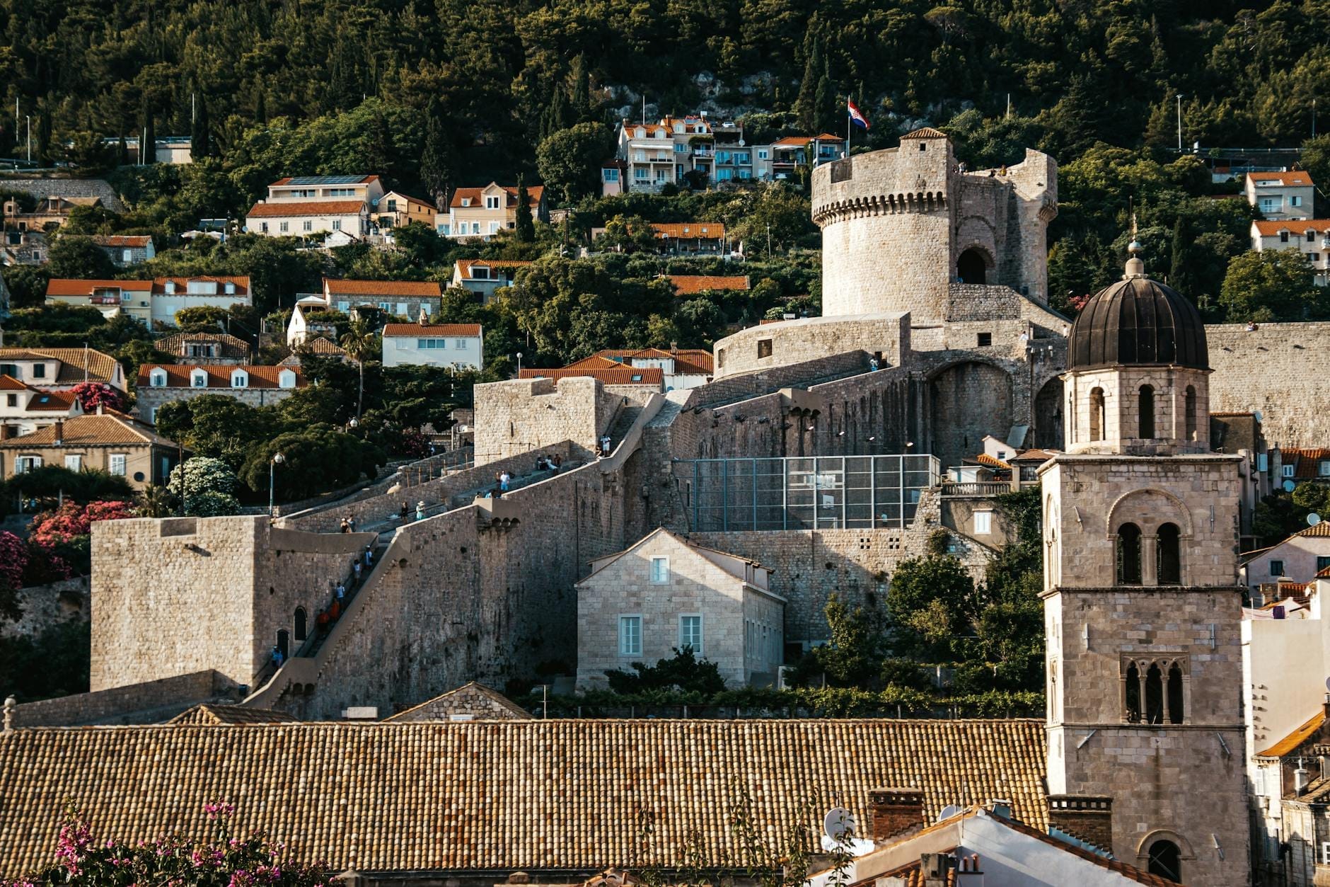 Vista de cerca de las murallas de Dubrovnik con la Torre Minčeta y la cúpula de una iglesia cercana, puntos destacados clásicos a lo largo del recorrido por las murallas.