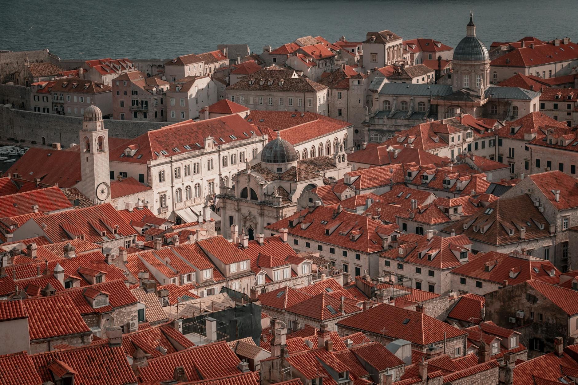 Vista sobre los tejados del casco antiguo de Dubrovnik con edificios históricos, cúpulas y torres de iglesias densamente agrupados dentro de las murallas de la ciudad.